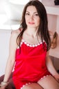 Beautiful and happy brunette woman in red pajamas or chemise poses in front of the camera in her bedroom Royalty Free Stock Photo