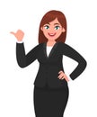 Beautiful happy business woman with formal suit pointing or showing thumb finger to copy space while standing.