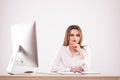 Beautiful happy businesswoman using computer while sitting at the desk at office on the white background Royalty Free Stock Photo