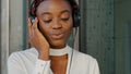 Beautiful happy carefree afro american girl african woman young lady mixed race female standing in city listening music Royalty Free Stock Photo