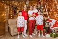 Beautiful happy Caucasoid family of five in white and red clothes for Christmas. children and parents