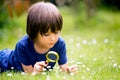 Beautiful happy child, boy, exploring nature with magnifying glass, summertime Royalty Free Stock Photo