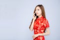 Beautiful happy Chinese New Year portrait young asian woman cheongsam dress talking smart mobile phone isolated