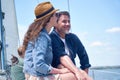 Beautiful happy couple enjoying sailing together, sitting on the side of sailboat, yacht. Selective focus on handsome man Royalty Free Stock Photo