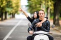 Beautiful happy couple riding scooter and having fun, woman pointed with hands and smiling. Royalty Free Stock Photo