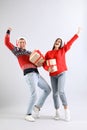 Beautiful happy couple in Santa hats with Christmas gifts having fun on light background Royalty Free Stock Photo
