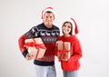 Beautiful happy couple in Santa hats holding Christmas gifts on light background Royalty Free Stock Photo