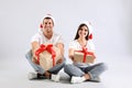 Beautiful happy couple in Santa hats sitting with Christmas gifts on light background Royalty Free Stock Photo