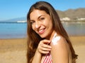 Beautiful happy cute woman applying suntan cream to her nose and shoulder with beach background Royalty Free Stock Photo