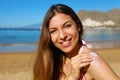 Beautiful happy cute woman applying suntan cream to her nose and shoulder with beach background Royalty Free Stock Photo