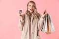 Beautiful happy excited young pretty woman posing isolated over pink wall background holding shopping bags and credit card Royalty Free Stock Photo