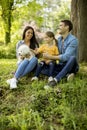 Beautiful happy family is having fun with bishon dog under the tree outdoors Royalty Free Stock Photo