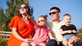 Beautiful happy family. They sit on a park bench, sunglasses. Little daughter pointing her finger at the sky Royalty Free Stock Photo