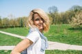 Beautiful happy female with blonde blowing hair, smiling and posing against nature background. Portrait of Caucasian young woman Royalty Free Stock Photo