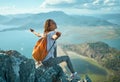 Happy female hikers on top of mountain enjoying valley view, sits on cliff with open arms.