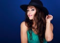 Beautiful happy female model with bright makeup and pink lipstick in black hat posing on blue background with long curly hair sty Royalty Free Stock Photo