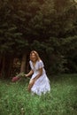 A beautiful happy girl in a long white dress bared her leg, laughing, holding an armful of wild flowers in her hand. Live photo.