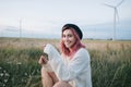 beautiful happy girl with pink hair in white sweater and hat sitting in field Royalty Free Stock Photo