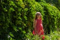 Beautiful happy girl in a red polka dot dress smiling on wild grape background. Cute joyful child with long blonde hair