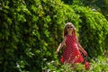 Beautiful happy girl in a red polka dot dress smiling on wild grape background. Cute joyful child with long blonde hair