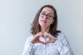 Beautiful happy girl smiling. Beauty simple portrait young woman in eyeglasses showing heart sign with hands isolated on white Royalty Free Stock Photo