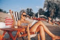 Smiling girl reading a book while sitting on deck chair Royalty Free Stock Photo