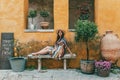 Portrait of woman wearing hat and dress, sitting in front of old orange building Royalty Free Stock Photo