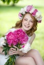 Beautiful happy girl in a wreath and with a bouquet of peonies Royalty Free Stock Photo