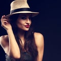 Beautiful happy grimacing female model with long brown hair posing in cowboy hat and fashion top on dark background. Closeup tone