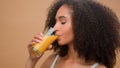 Beautiful happy healthy African American woman ethnic girl female model with curly hair drinking fresh orange juice Royalty Free Stock Photo