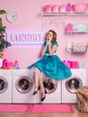 Beautiful happy housewife wipes the dust. woman in retro 60s pin-up style in the laundry. Home wash. Housekeeper at work.