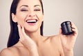 Beautiful happy laughing woman holding jar of skin cream. Smiling female model applying skincare moisturizer the hand on face and Royalty Free Stock Photo