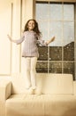 Beautiful happy Lille girl jumping on sofa Royalty Free Stock Photo