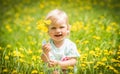 Beautiful happy little baby girl sitting on a green meadow with yellow flowers dandelions Royalty Free Stock Photo