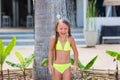 Beautiful happy little girl in a yellow bathing suit under a shower on the beach in a tropical garden Royalty Free Stock Photo