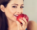 Beautiful happy makeup woman holding red tasty apple and biting