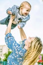 Beautiful happy mather with baby boy holding it up outdoor on nature