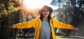 Beautiful happy senior mature woman in hat and yellow jacket enjoying nature in the park stretching her arms Royalty Free Stock Photo