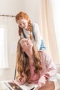 Beautiful happy mother and daughter reading book and smiling each other at home Royalty Free Stock Photo