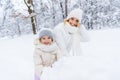 beautiful happy mother and daughter smiling at camera while making snowman
