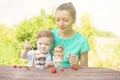 Beautiful happy mother and her child boy eating layered dessert in green garden in sunny summer day