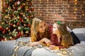 Beautiful happy mother with her ittle daughter are enjoying near christmas tree in modern decorated home, Happy New year