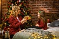 Beautiful happy mother with her ittle daughter are enjoying near christmas tree in modern decorated home, Happy New year