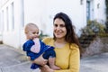 Beautiful happy mother holding her cute baby in peaceful neighborhood Royalty Free Stock Photo