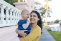 Beautiful happy mother holding her cute baby in peaceful neighborhood Royalty Free Stock Photo