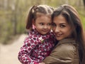 Beautiful happy mother and kid girl cuddling outdoors