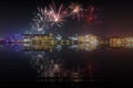 Beautiful happy new year fireworks above a city skyline with reflections on water Royalty Free Stock Photo