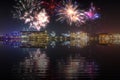 Beautiful happy new year fireworks above a city skyline with reflections on water Royalty Free Stock Photo