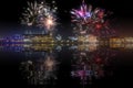 Beautiful happy new year fireworks above a city skyline with reflections on water Royalty Free Stock Photo