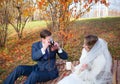 Beautiful happy newly married couple sitting on plaid in park, g